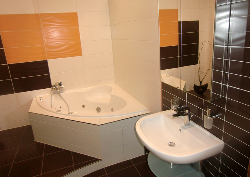Modernes Badezimmer weiß gefliest, aufgelockert mit farbigen, orangen und schwarzen Fliesen, Eckbadewanne mit Massagefunktion